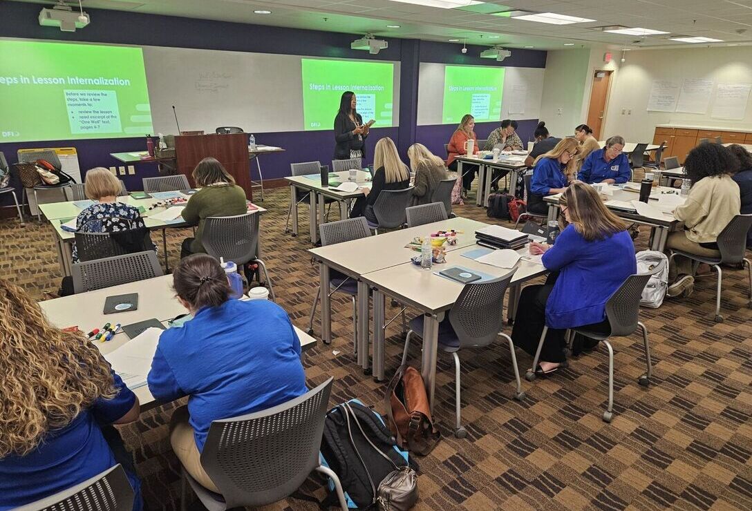 DFI staff standing in front of a large classroom of teacher-educators