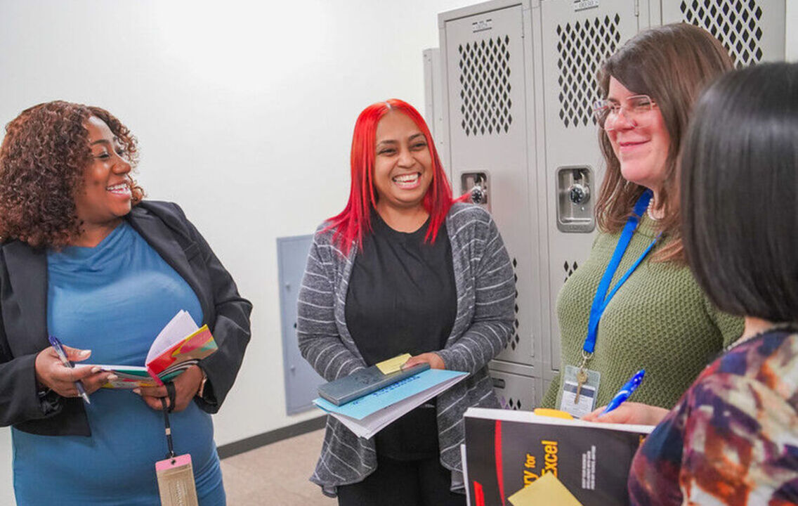A group of four educators standing together and laughing
