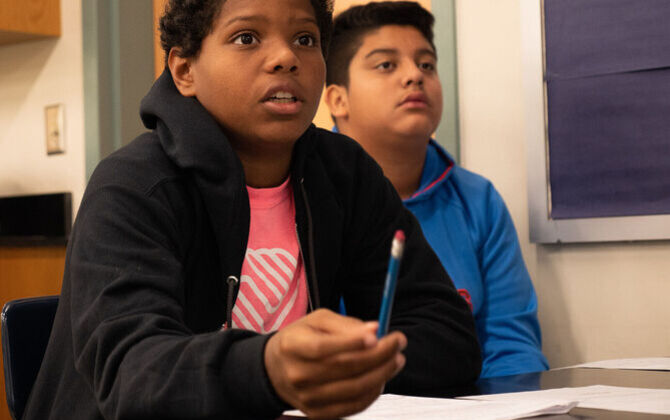 Two students looking up at the front of the classroom