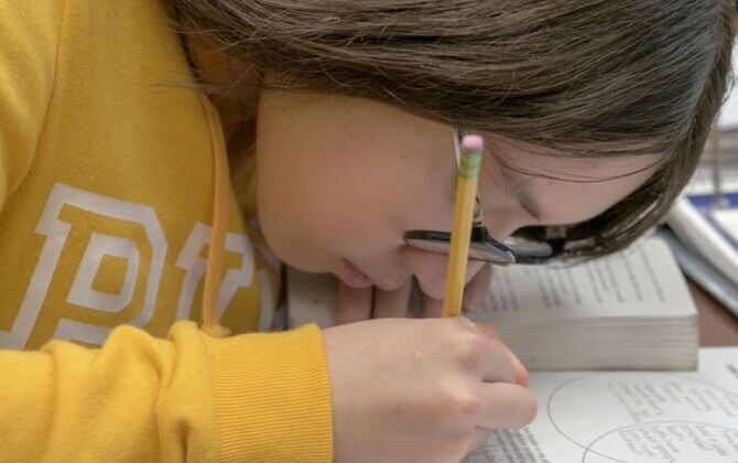 Student leaning in closely to complete a worksheet