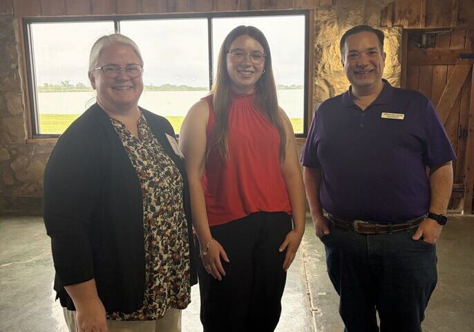 Taylor standing for a photo in between two faculty members