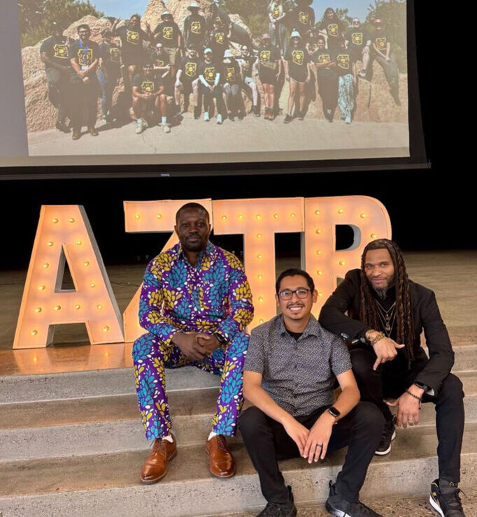 Three aspiring teacher sitting on steps with a large 