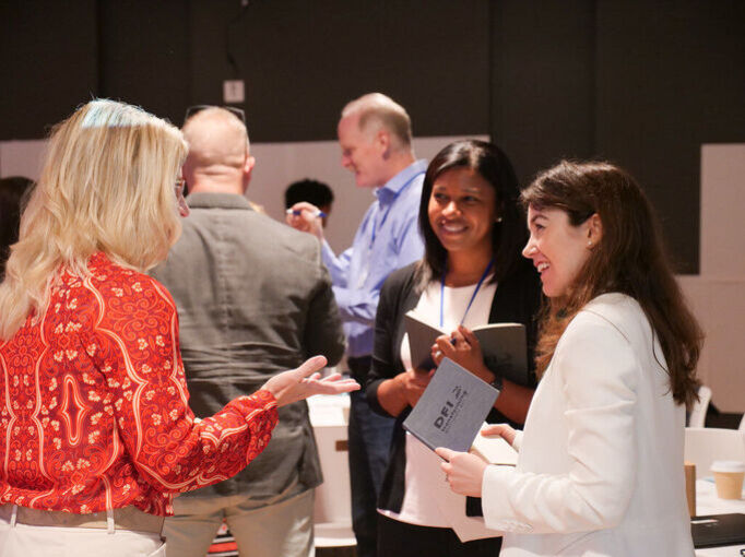 Victoria Theisen-Homer standing in a small group conversation with two other women